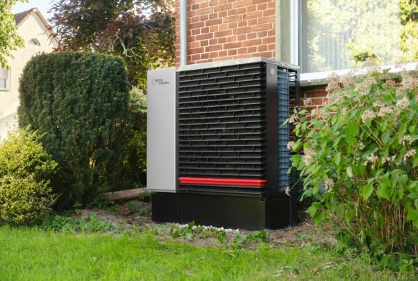 Pompe à chaleur air-eau installée contre le mur d'une maison en briques