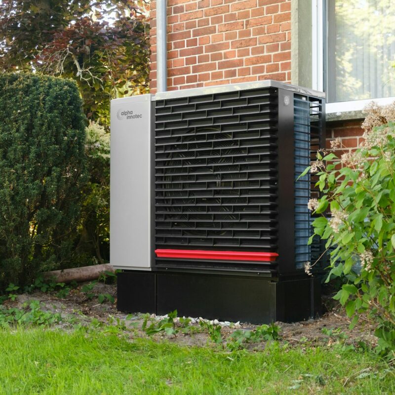 Pompe à chaleur air-eau installée contre le mur d'une maison en briques